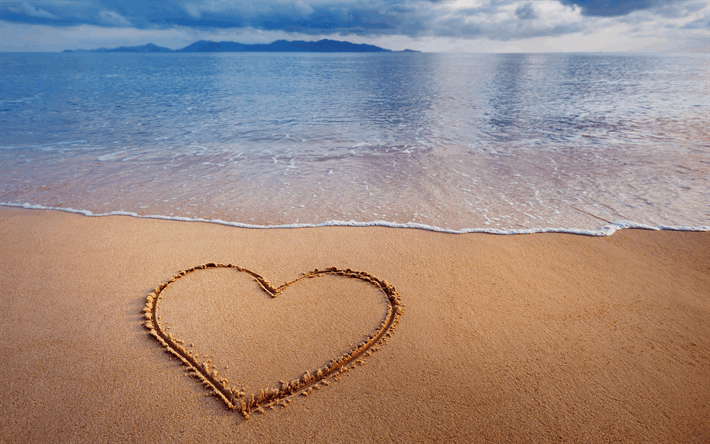 Un cuore disegnato sulla sabbia in riva al mare